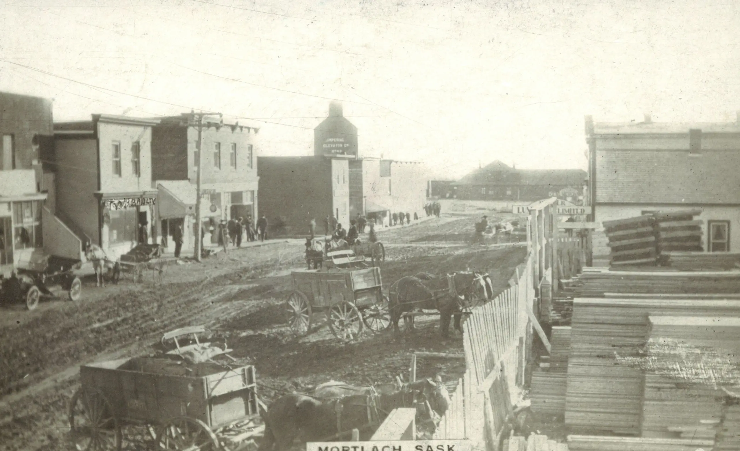 Mortlach street scene with horse-drawn wagons and lumber pile