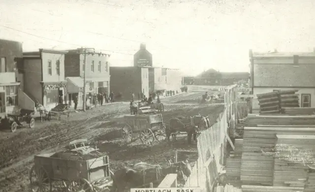 Mortlach street scene with horse-drawn wagons and lumber pile